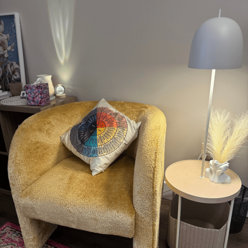 Yellow chair with pillow, side table, and lamp in Cynthia’s Confidence Coaching & Counseling office