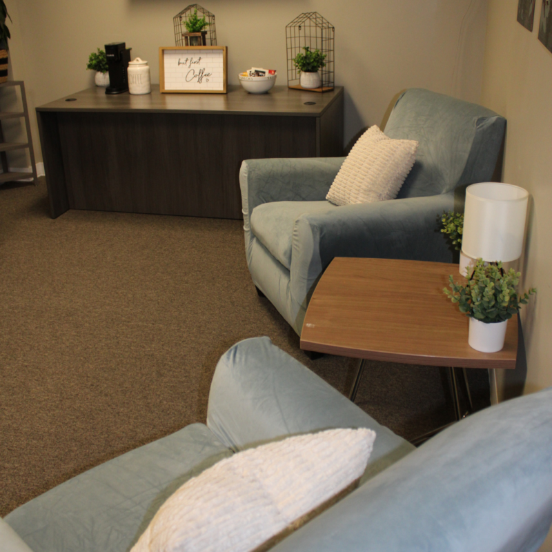 Mountains Therapy room with two blue chairs, a coffee table, and a long table against the wall