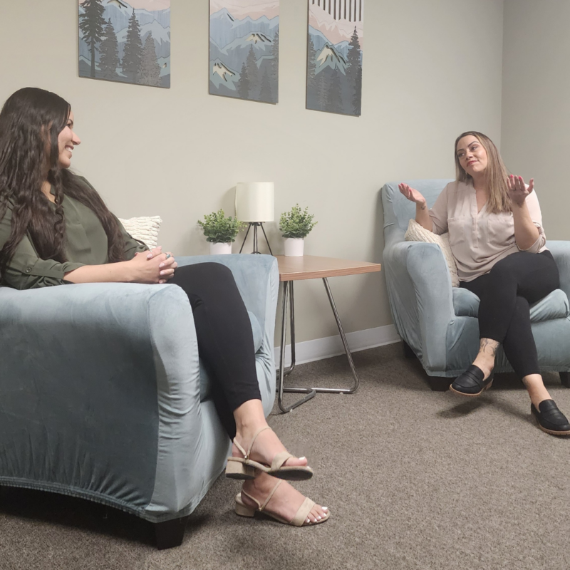 Mountains Therapy Founder Christina Andino, LCSW, MSW speaking with a client in blue chairs