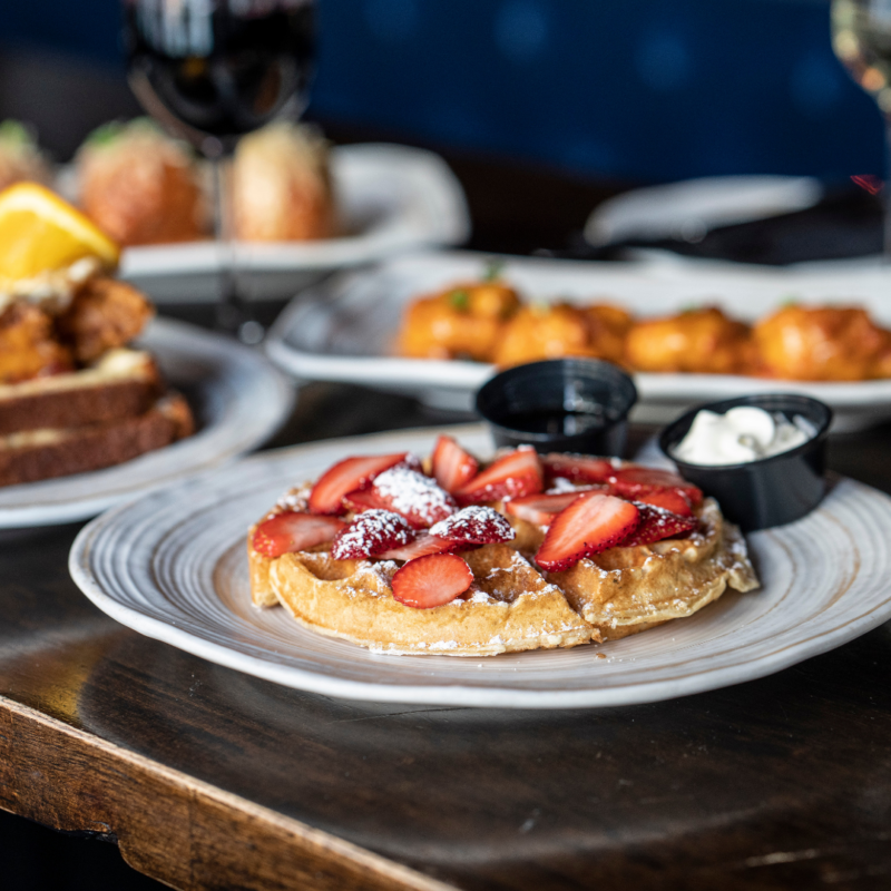 Brunch dishes including waffle with strawberries and whipped cream