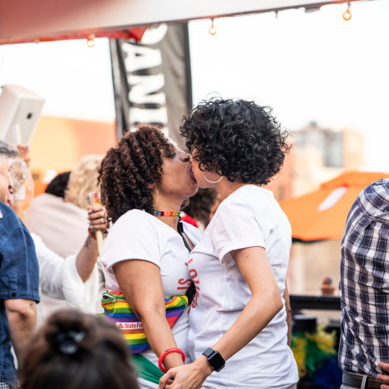 Two women kissing and holding hands on Six26 rooftop