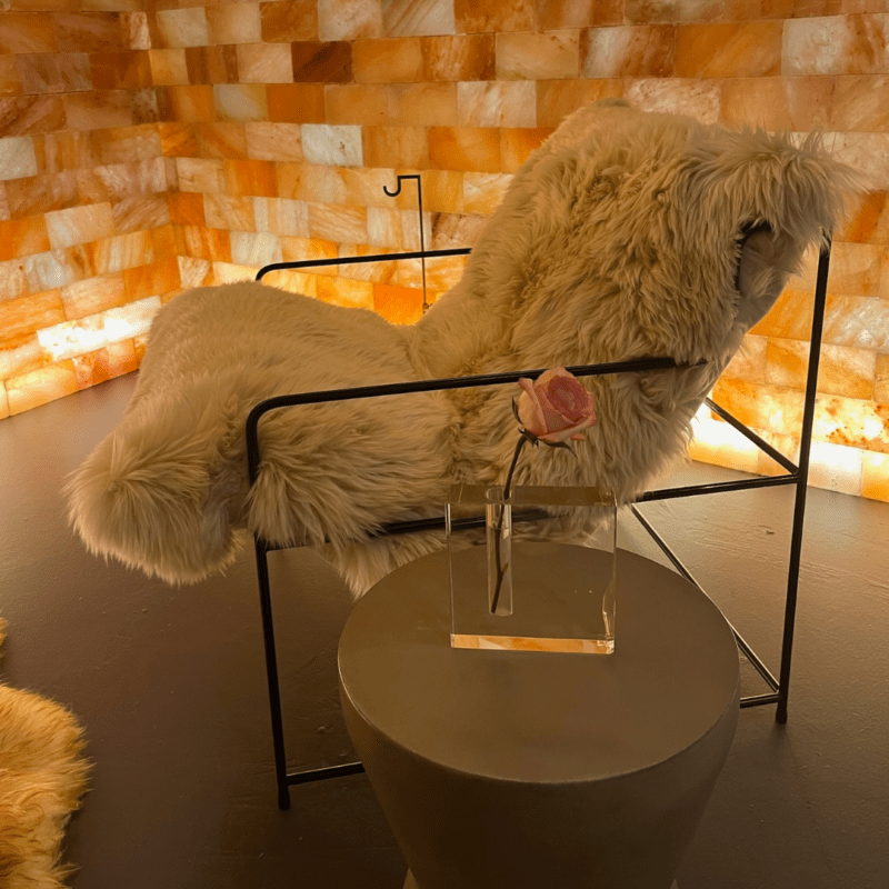 Chair with side table with rose in salt room with orange walls