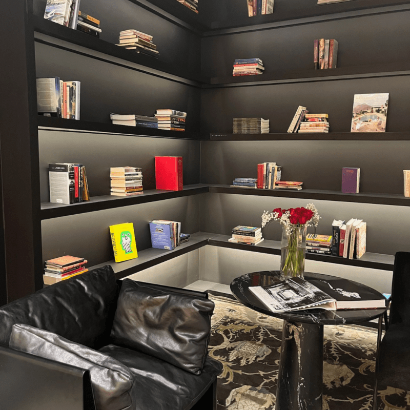 Oasis library with black chair, table with rose, and large bookshelves on the walls
