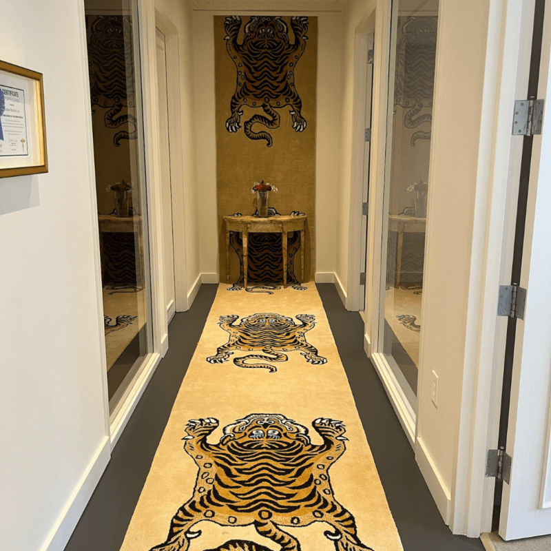Oasis hallway with multiple doors open and a yellow rug and wallpaper with tigers.