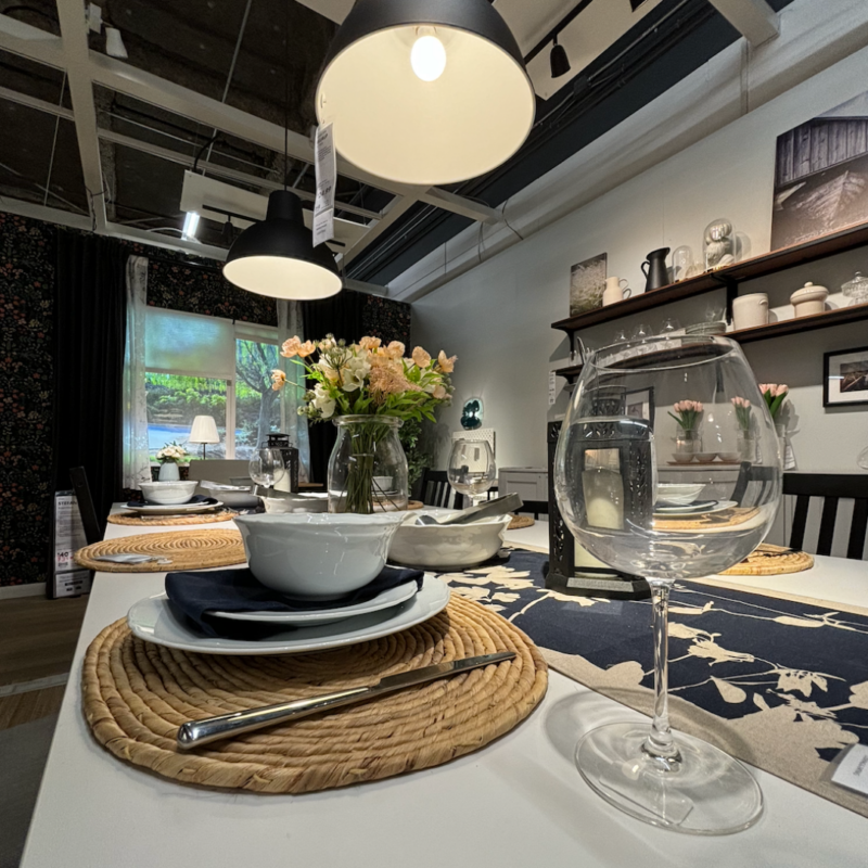 Staged dining room in IKEA Elizabeth with a close-up of a plate setting with wine glass, plate, bowl, and knife