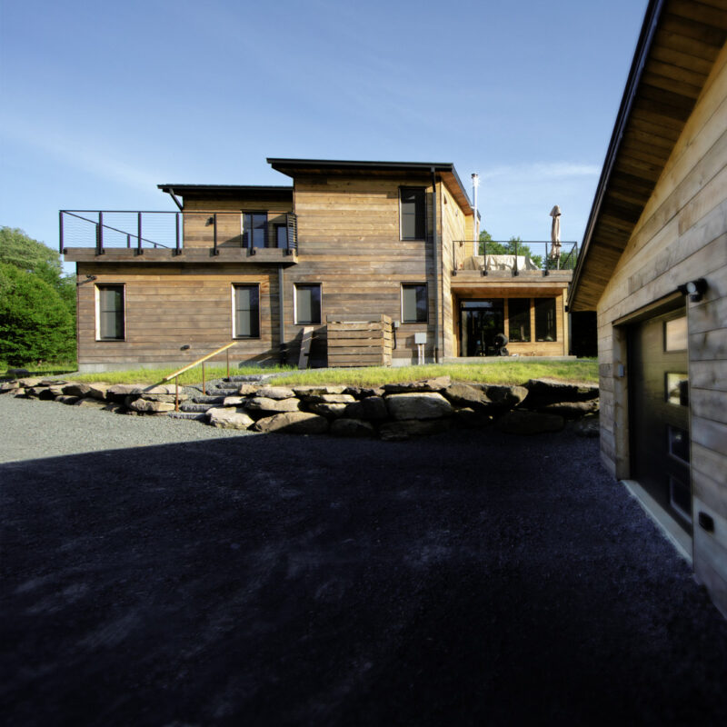 Multi-story wood home with large deck and blue skies in the background