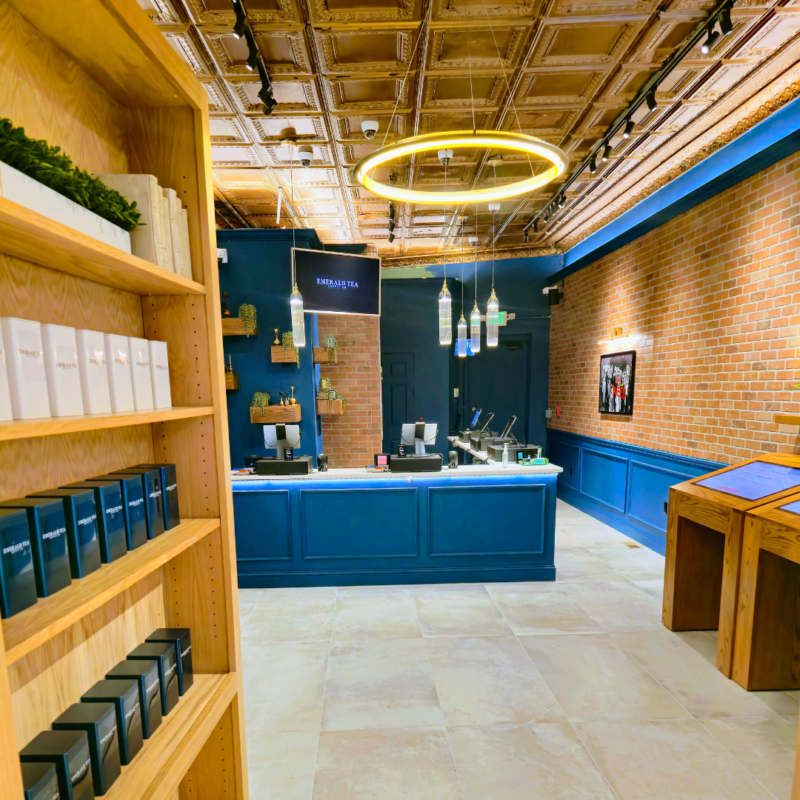 Emerald Tea Supply Co shop with exposed brick walls, blue checkout counter, and products on wood shelves
