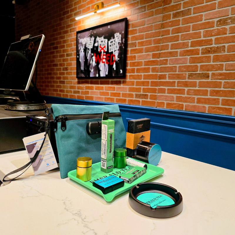 Selection of cannabis products and accessories on the counter at Emerald Tea Supply Co with register and exposed brick wall in background