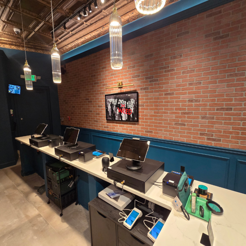 Checkout counter at Emerald Tea Supply Counter Co with three registers and exposed brick wall