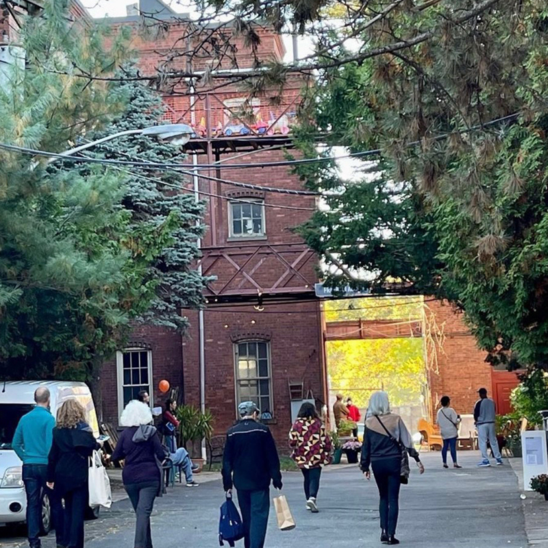 Exterior view of people walking by brick building near trees at Manufacturers Village 