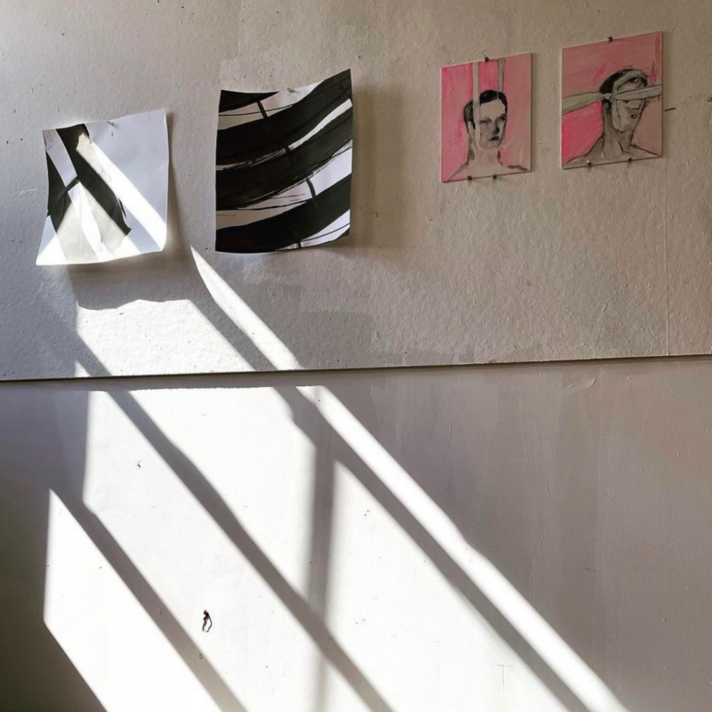 White wall with shadows and sunbeams and four pieces of art
