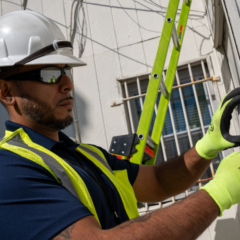 Man in a yellow vest and white hard hat working outside a house
